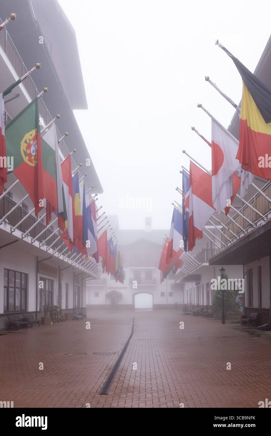 SOCHI, RUSSIA - 3 MAGGIO 2024: Villaggio olimpico con vista su edifici e bandiere nazionali di diversi paesi in una giornata primaverile nebbiosa Foto Stock
