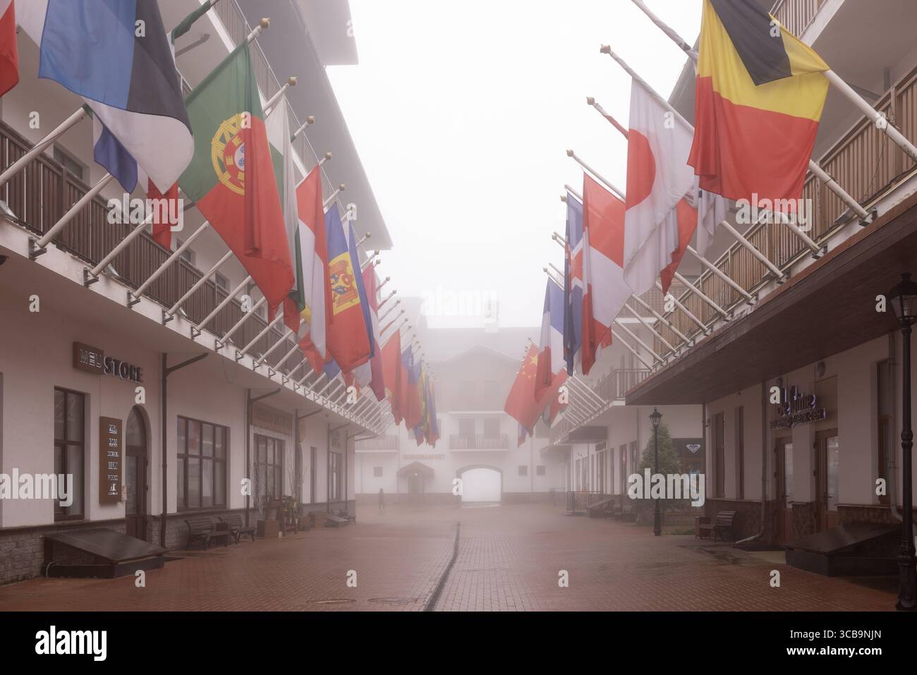 SOCHI, RUSSIA - 3 MAGGIO 2024: Un uomo cammina attraverso il villaggio olimpico, il villaggio olimpico con vista sugli edifici e le bandiere nazionali di diversi paesi Foto Stock
