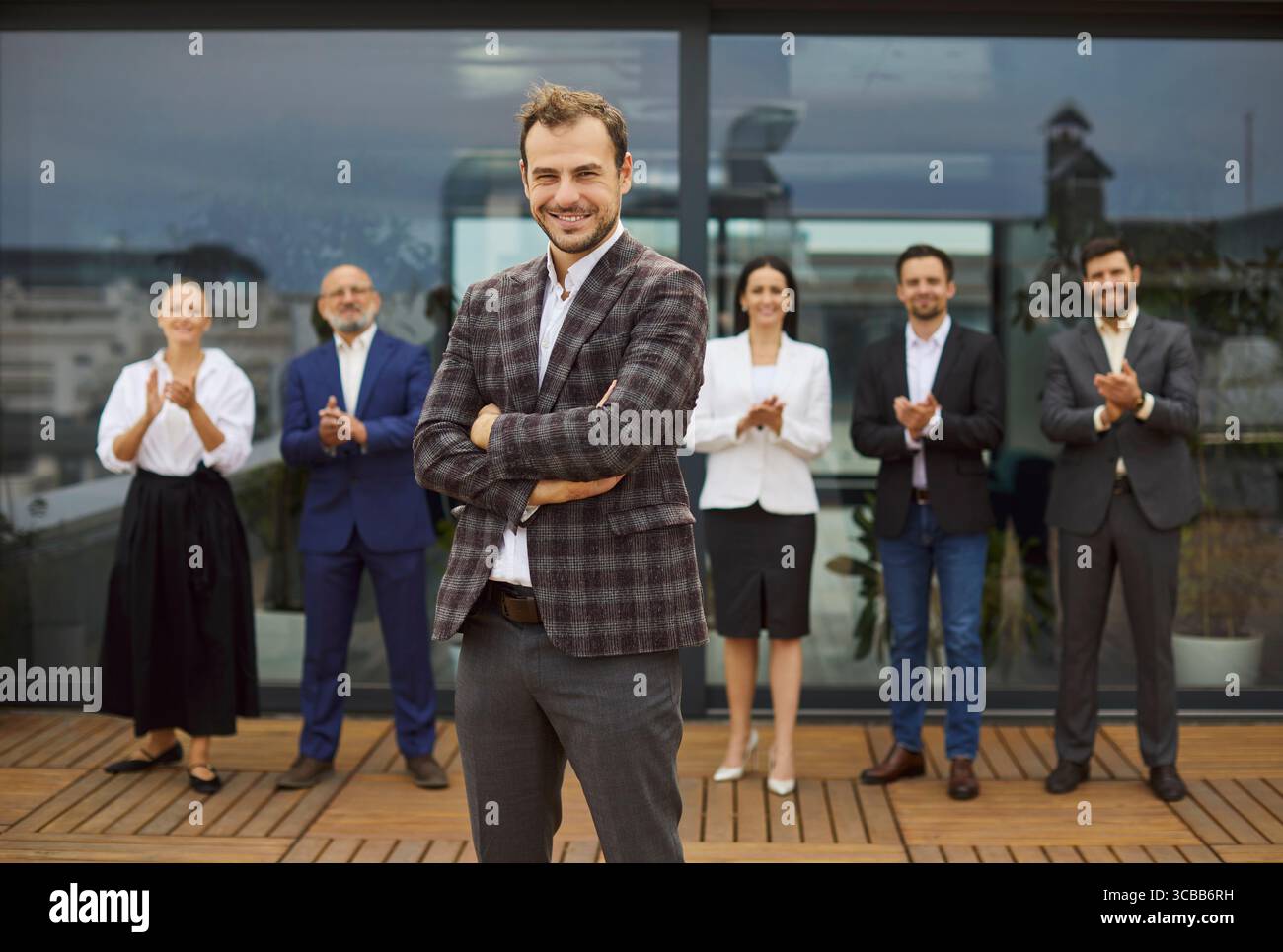 Leader aziendale fiducioso davanti al gruppo di dipendenti applaudito vicino all'edificio degli uffici Foto Stock