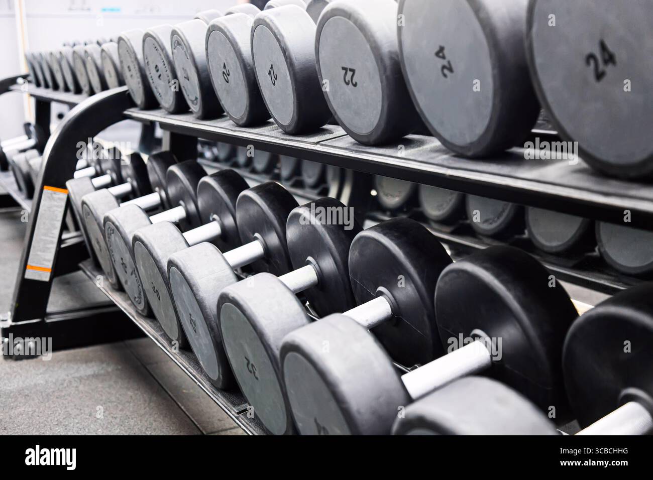 Concetto di sport fitness. Set di manubri neri. Avvicinati a molti manubri in metallo sul rack nel centro fitness sportivo Foto Stock