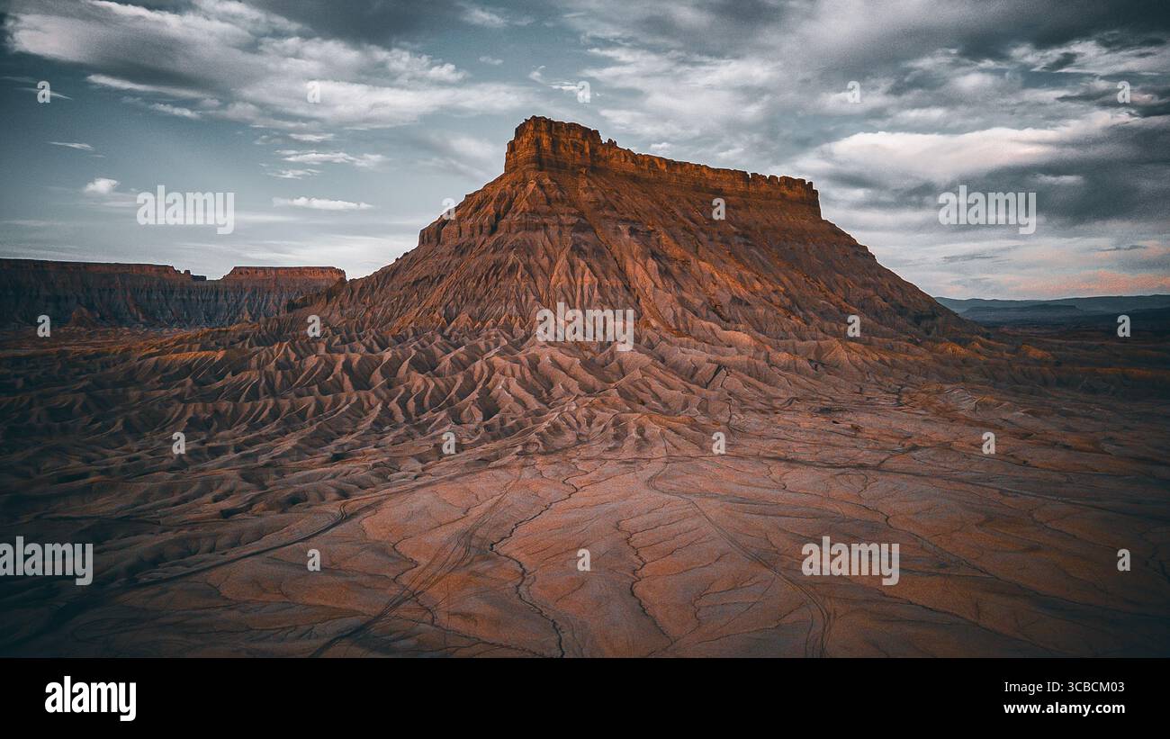 L'iconica mesa del deserto solitario che sorge da motivi di terra profondamente incisi Foto Stock