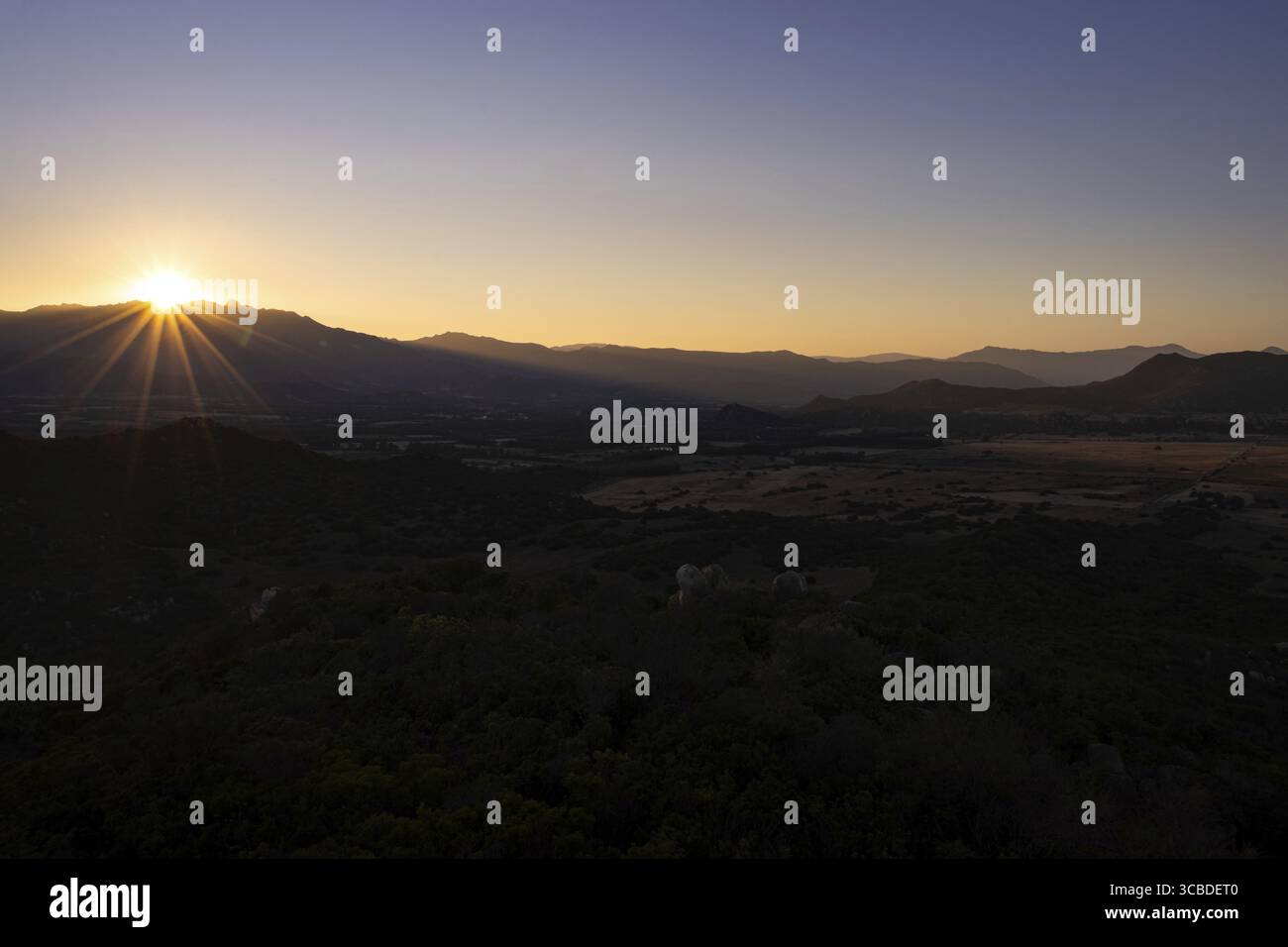 Il sole tramonta dietro le montagne dell'isola mediterranea della Sardegna, Monte Nai, Costa Rei, Sardegna, Italia Foto Stock