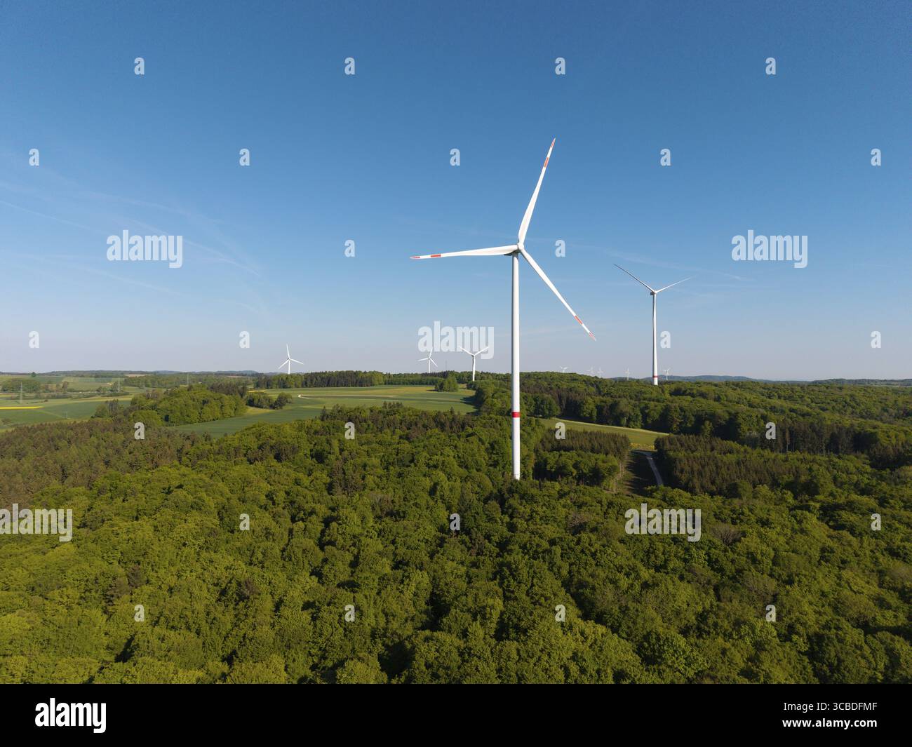 Paesaggio di turbine eoliche nel mezzo di una foresta sotto un cielo blu, vicino a Westerheim, Svevia Alb, Baden-Wuerttemberg, Germania Foto Stock
