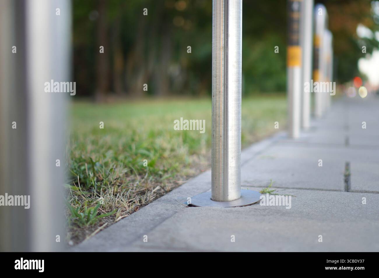 Primo piano di un dissuasore in acciaio inossidabile installato su un marciapiede pavimentato per proteggere i pedoni e contrassegnare l'accesso limitato al veicolo in un ambiente urbano moderno Foto Stock