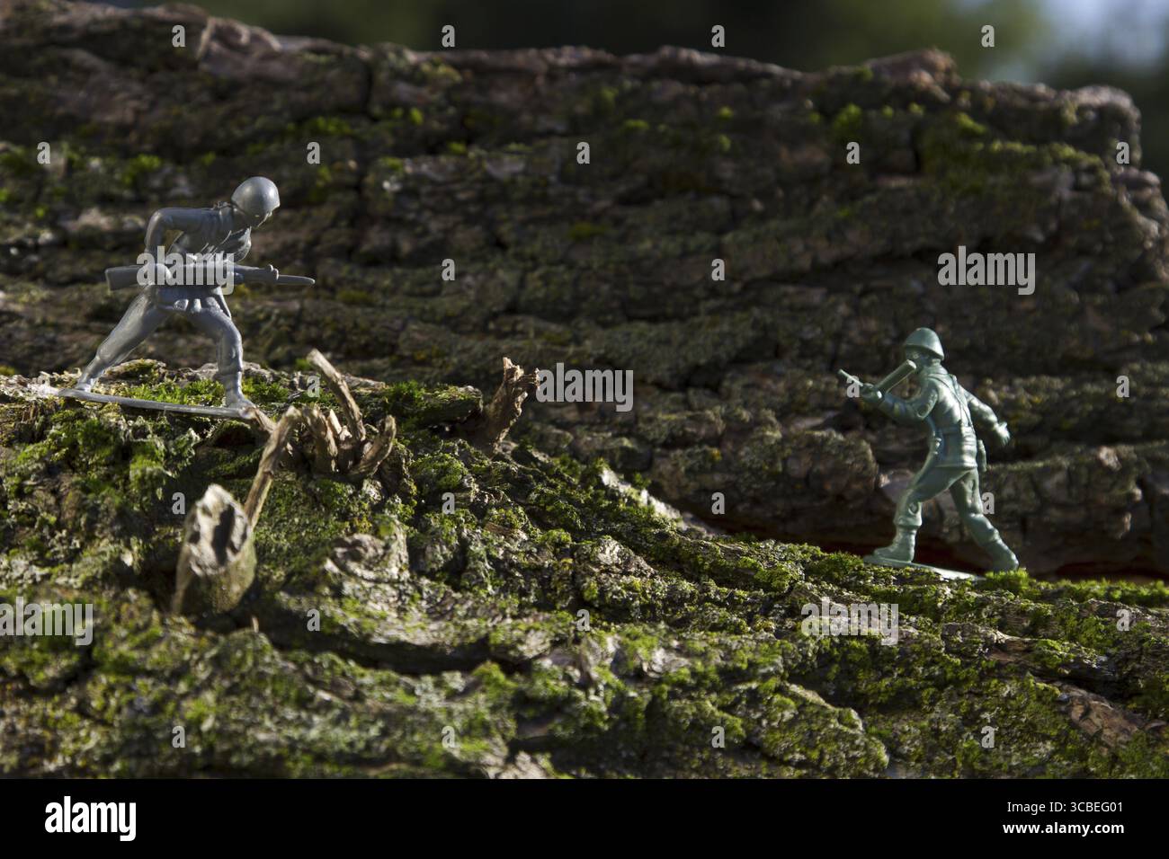 Un soldato di plastica grigio e verde nel bel mezzo di una battaglia sulla cima del legno Foto Stock