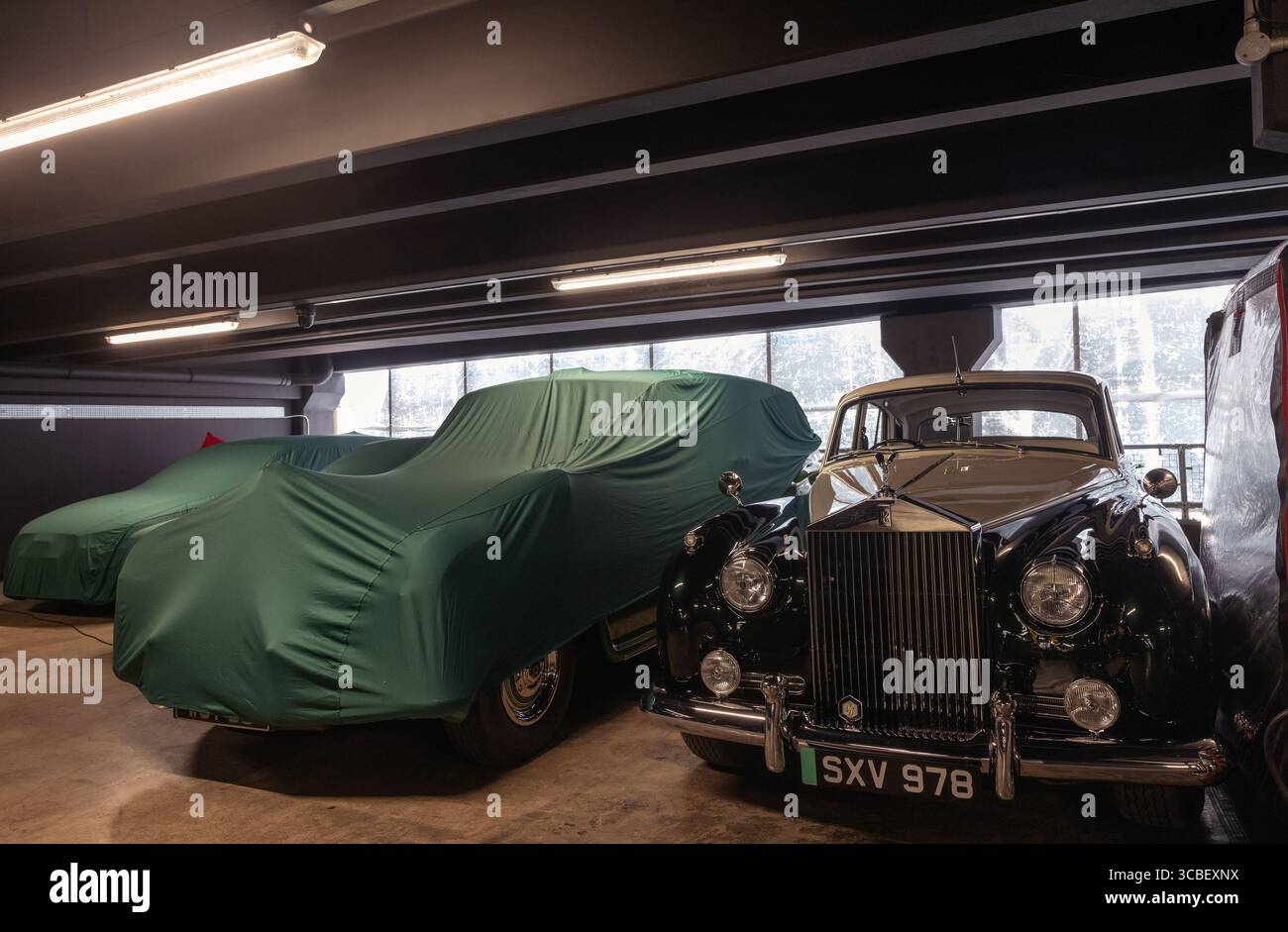 auto rolls-royce di lusso coperte da teli protettivi all'interno di un garage, che mostrano una conservazione sicura a lungo termine di alta qualità Foto Stock