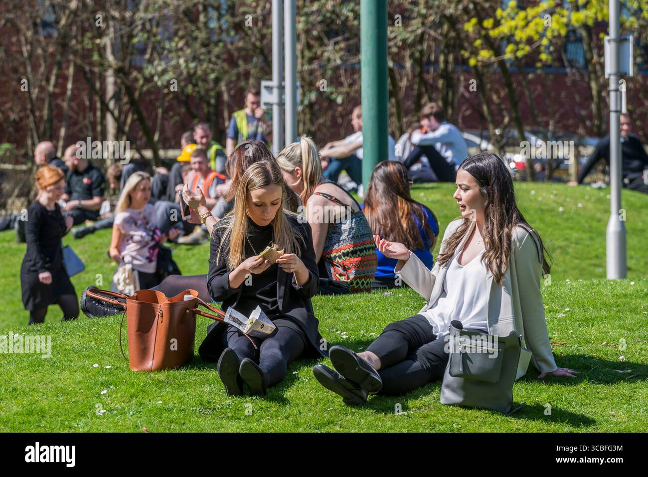 Turisti e lavoratori seduti lungo lo storico lungomare di Albert Dock a Liverpool, una delle principali attrazioni turistiche del Regno Unito. Foto Stock