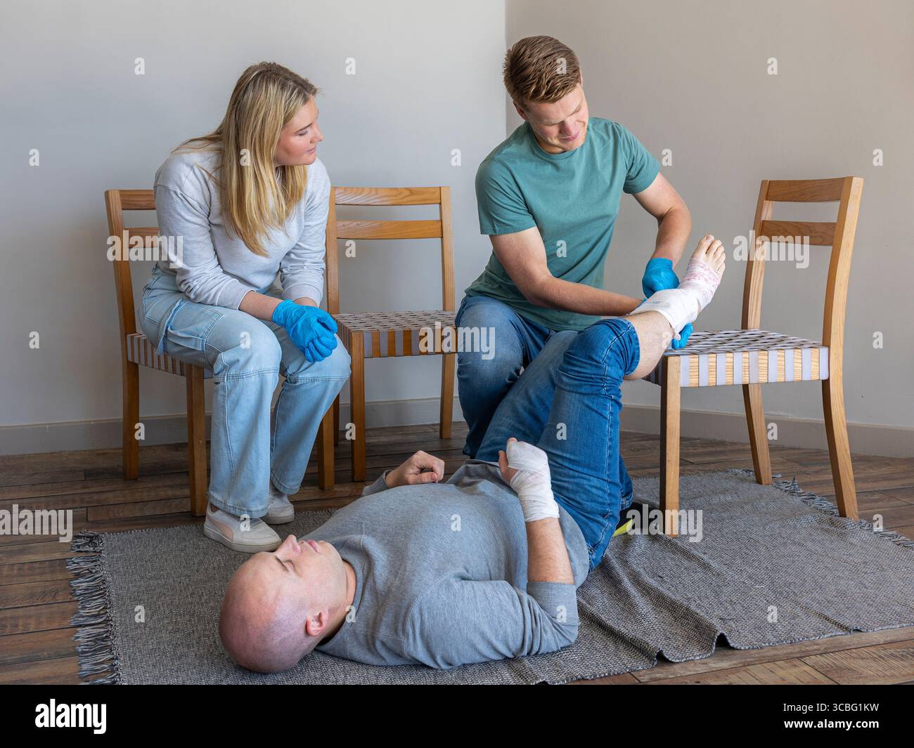 Classe di pronto soccorso pratica fasciatura caviglia, paziente con istruttore che aiuta e insegna Foto Stock
