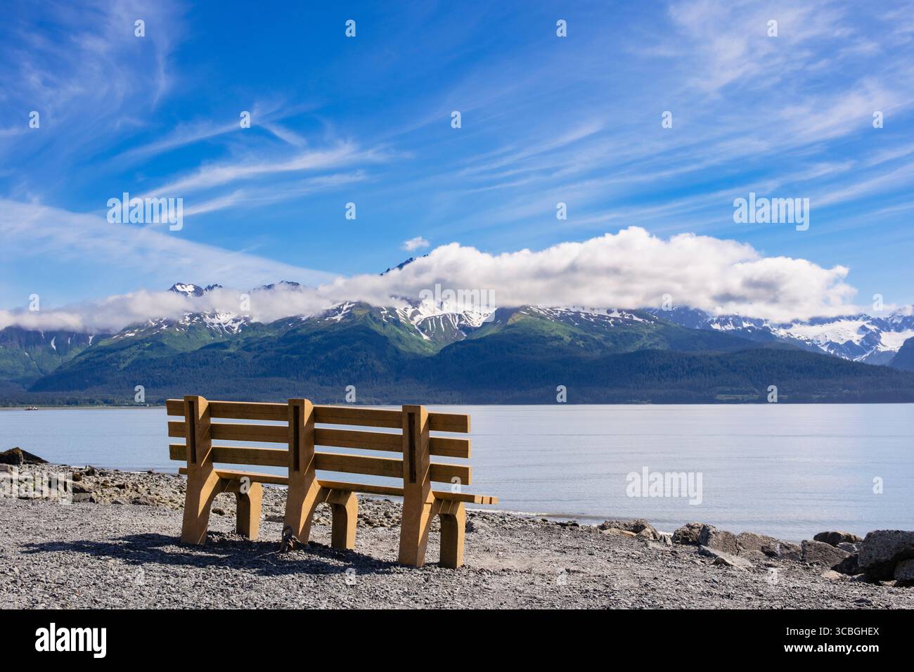 Posto a panchina vuoto sulla riva del mare che guarda verso il Monte Alice e il Ghiacciaio Godwin attraverso la Resurrection Bay sulla costa meridionale dell'Alaska. Seward, Alaska Foto Stock