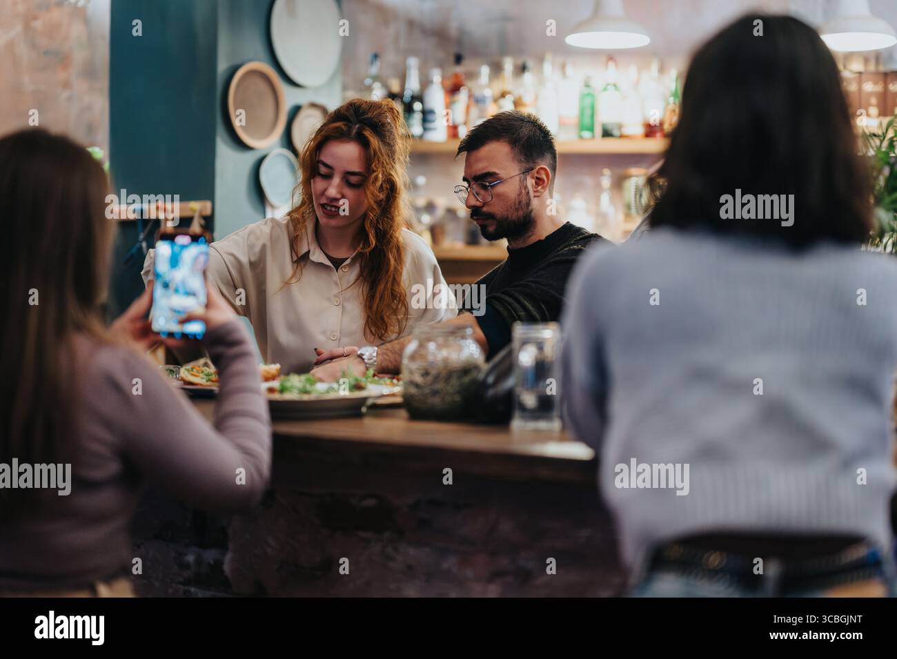 Gruppi di amici che si godono la preparazione del cibo in un accogliente lounge bar Foto Stock