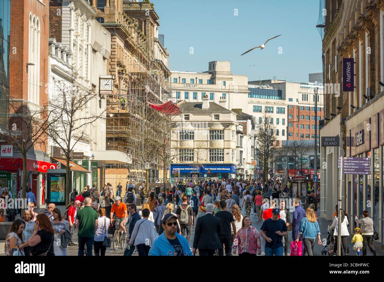 Folle di acquirenti in una trafficata strada di negozi nel centro di Liverpool con negozi, banche ed edifici storici. Foto Stock