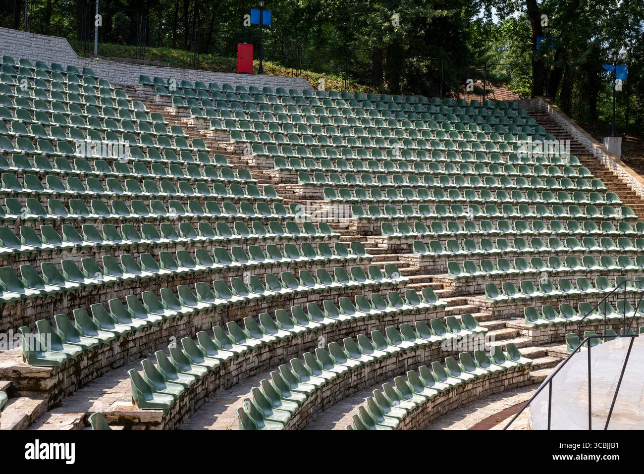 Il grande anfiteatro in pietra all'aperto è pieno di numerose file di sedili in plastica verde disposti in uno schema semicircolare Foto Stock