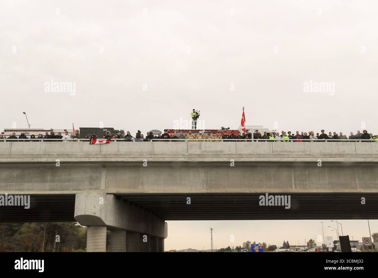 14 ottobre 2022, Innisfil, Ontario, Canada: Un giocatore solitario di cornamuse visto con servizi di emergenza e pubblico che tiene bandiere canadesi sul cavalcavia Big Bay Point Highway 400 preparandosi a salutare la processione di due agenti della polizia di South Simcoe uccisi che hanno risposto a una chiamata di disturbo domestico ad Alcona (Innisfil), Ontario - una piccola città nel centro-sud dell'Ontario, a circa un'ora a nord di Toronto. (Immagine di credito: © Christopher Drost/SHIFT digital tramite ZUMA Press Wire) Foto Stock
