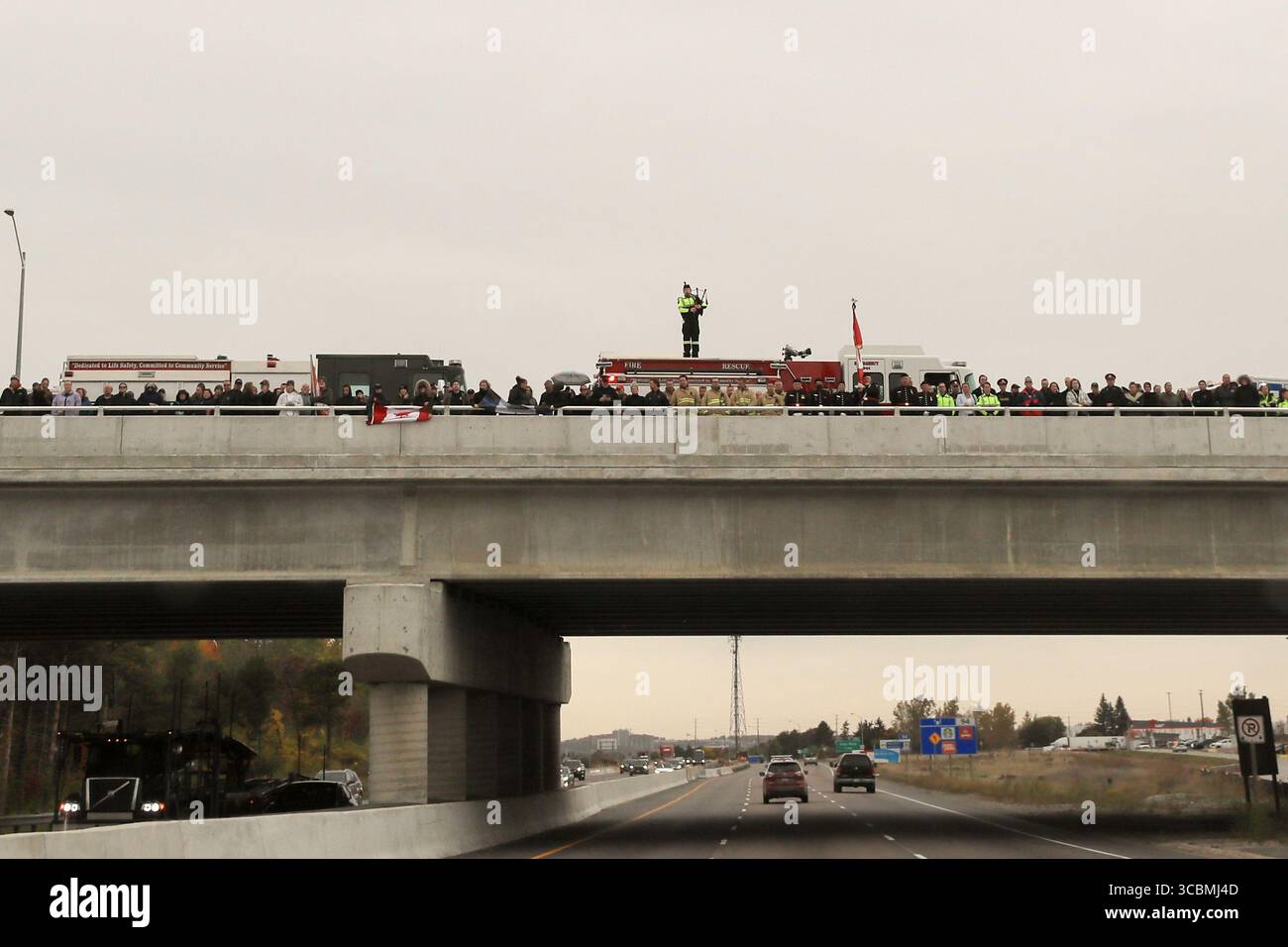 14 ottobre 2022, Innisfil, Ontario, Canada: Un giocatore solitario di cornamuse visto con servizi di emergenza e pubblico che tiene bandiere canadesi sul cavalcavia Big Bay Point Highway 400 preparandosi a salutare la processione di due agenti della polizia di South Simcoe uccisi che hanno risposto a una chiamata di disturbo domestico ad Alcona (Innisfil), Ontario - una piccola città nel centro-sud dell'Ontario, a circa un'ora a nord di Toronto. (Immagine di credito: © Christopher Drost/SHIFT digital tramite ZUMA Press Wire) Foto Stock