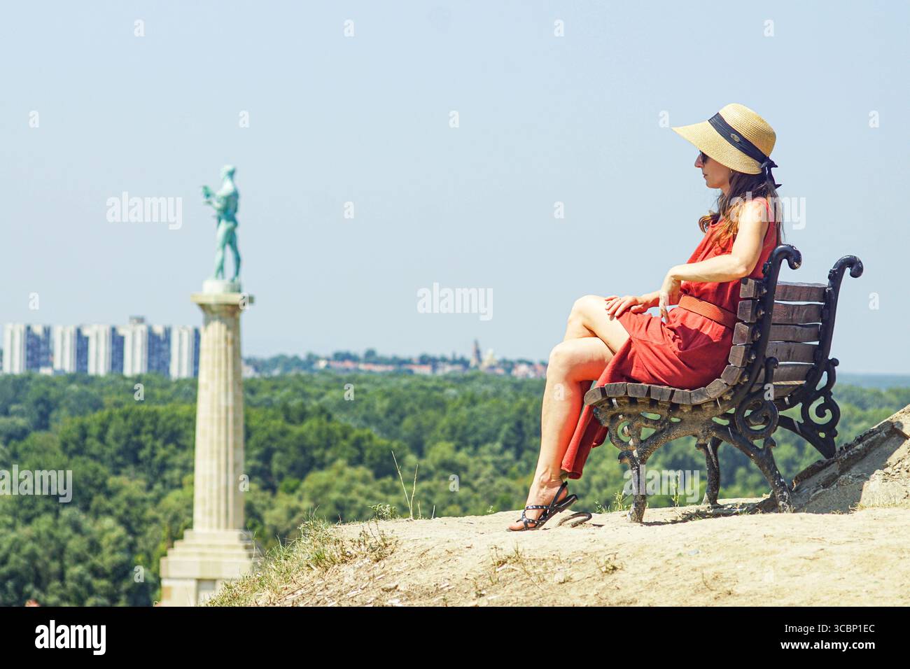 Stile di viaggio rilassato: Una donna con occhiali da sole, abito lungo e cappello ammira la vista dalla fortezza di Belgrado in Serbia. Assaporare momenti durante il viaggio Foto Stock