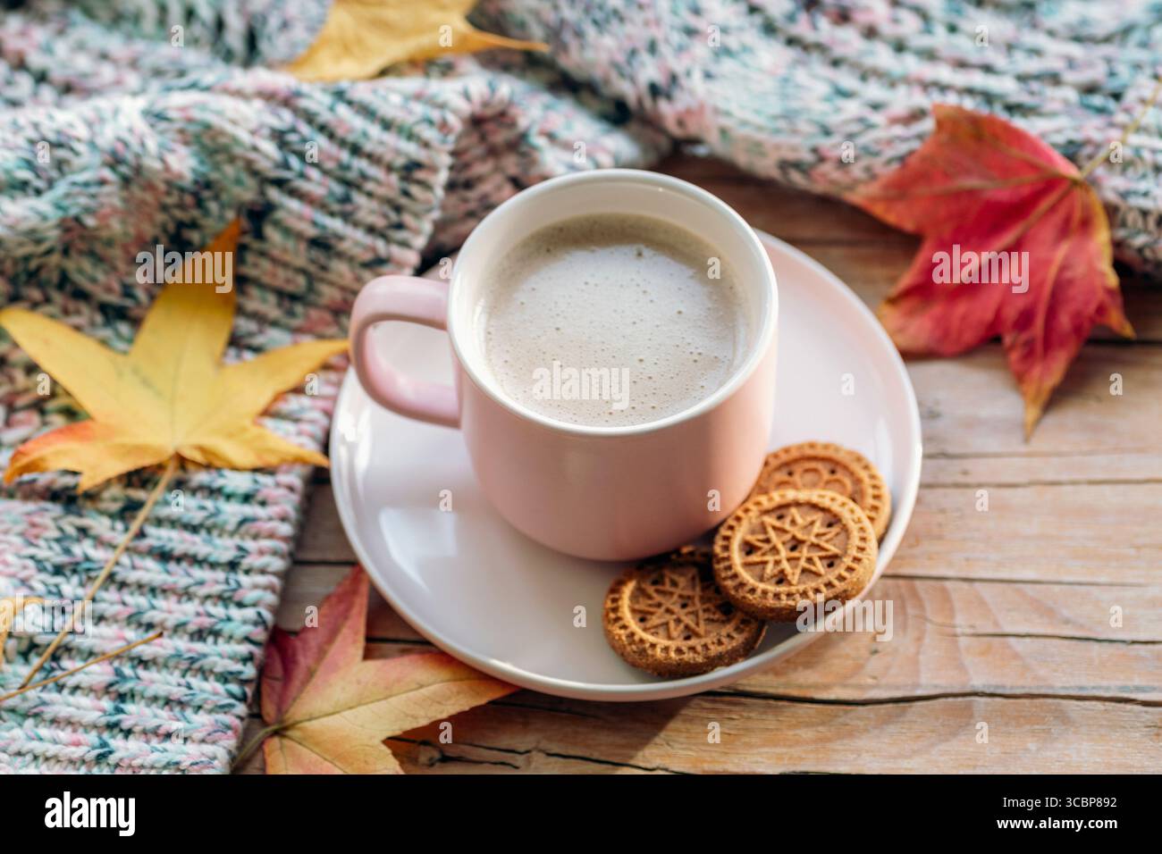Tazza di caffè con biscotti e foglie autunnali su un tavolo di legno con maglione caldo. Vista dall'alto. Foto Stock