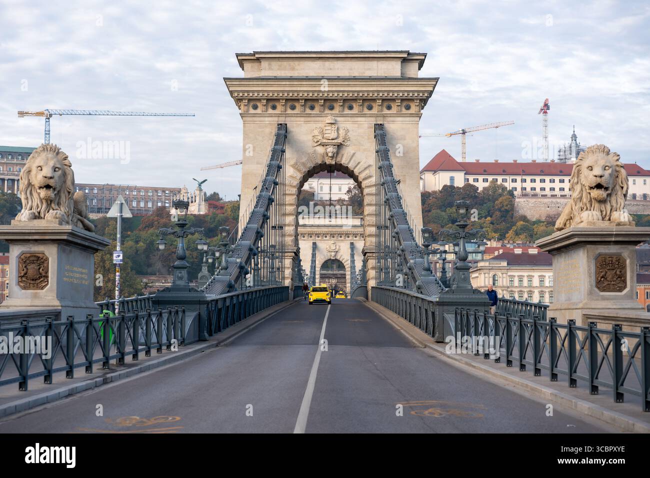 Ponte delle catene di Budapest durante il giorno con statue di leoni e attraversamento in taxi giallo, che mette in risalto la storica architettura ungherese europea Foto Stock