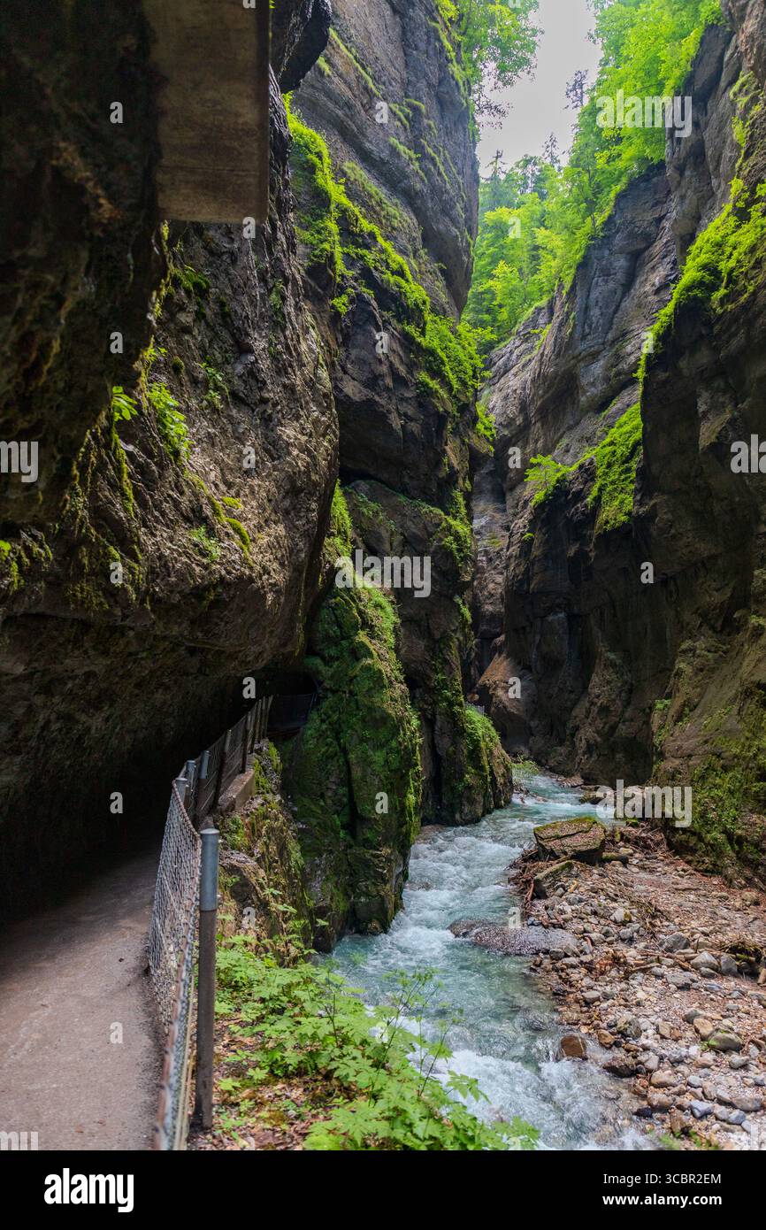 Stretta passerella scavata sulla scogliera lungo un torrente turchese all'interno della gola di Partnachklamm, Garmisch-Partenkirchen, Baviera. Uno splendido pass naturale Foto Stock