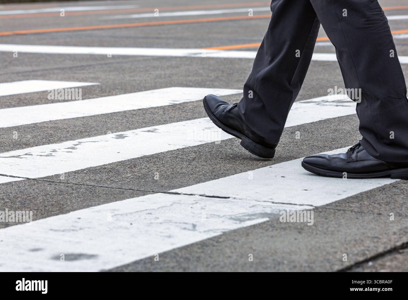 Vista dall'angolo basso, l'addetto alle vendite giapponese attraversa la zona pedonale in un ambiente urbano. Lo stile consiste nell'informale e fresco abbigliamento da lavoro estivo giapponese. Foto Stock