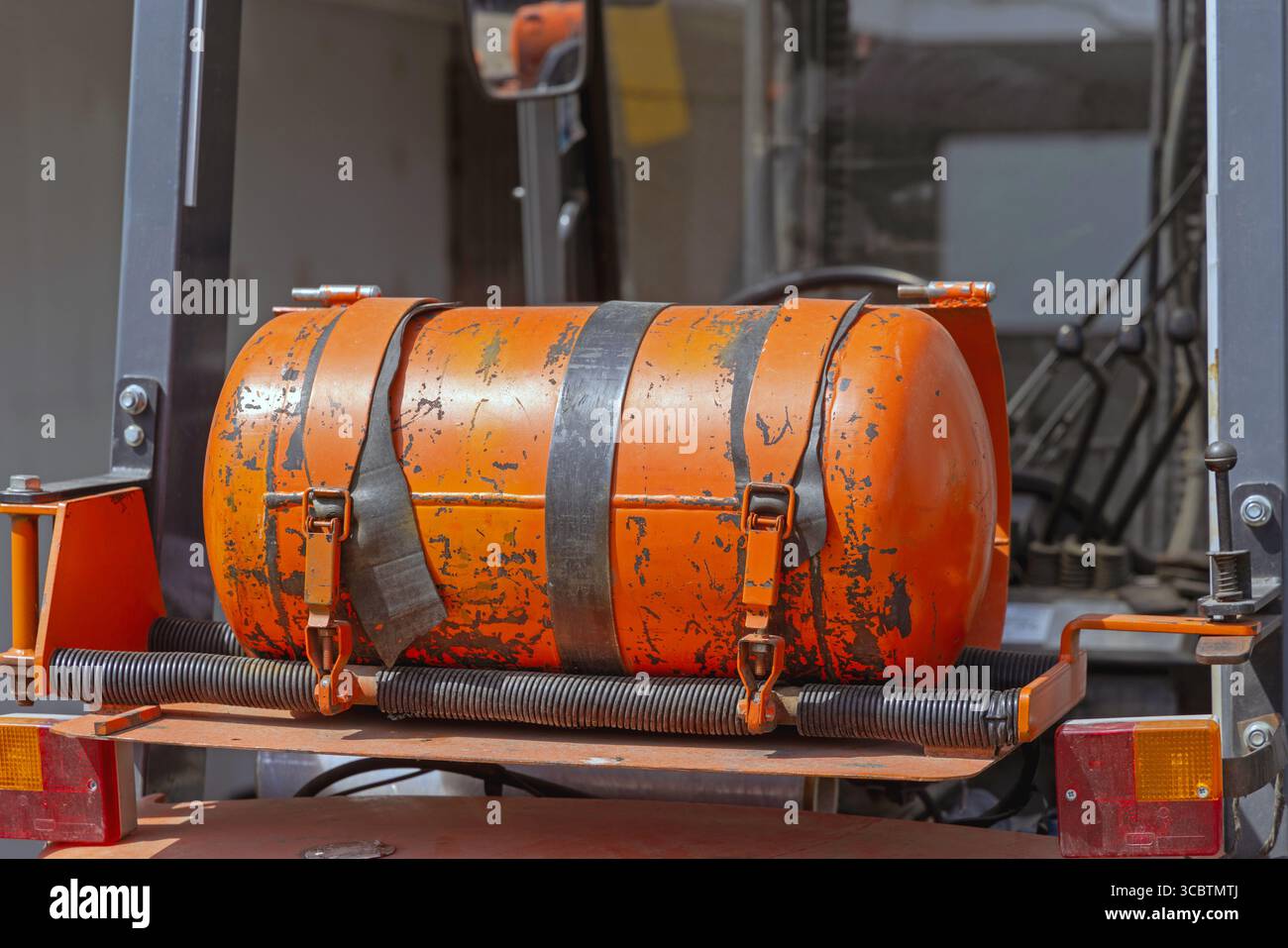 Bottiglia arancione per GPL montata orizzontalmente sul carrello elevatore a forche alimentato a gas Foto Stock