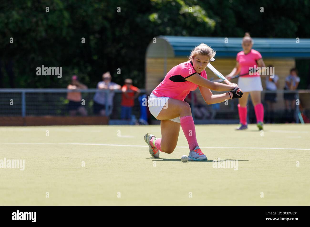 Un giocatore in uniforme rosa colpisce abilmente la palla durante la partita di hockey su prato Foto Stock
