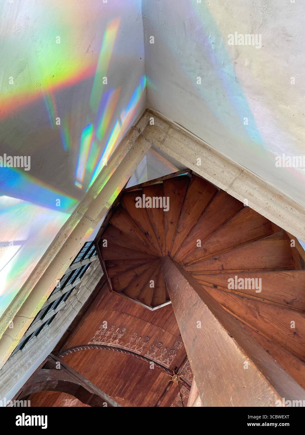 angolo di luce non tradizionale rifrangente in uno spazio geometricamente diverso da una finestra di vetro colorato in una chiesa su una scala di legno Foto Stock