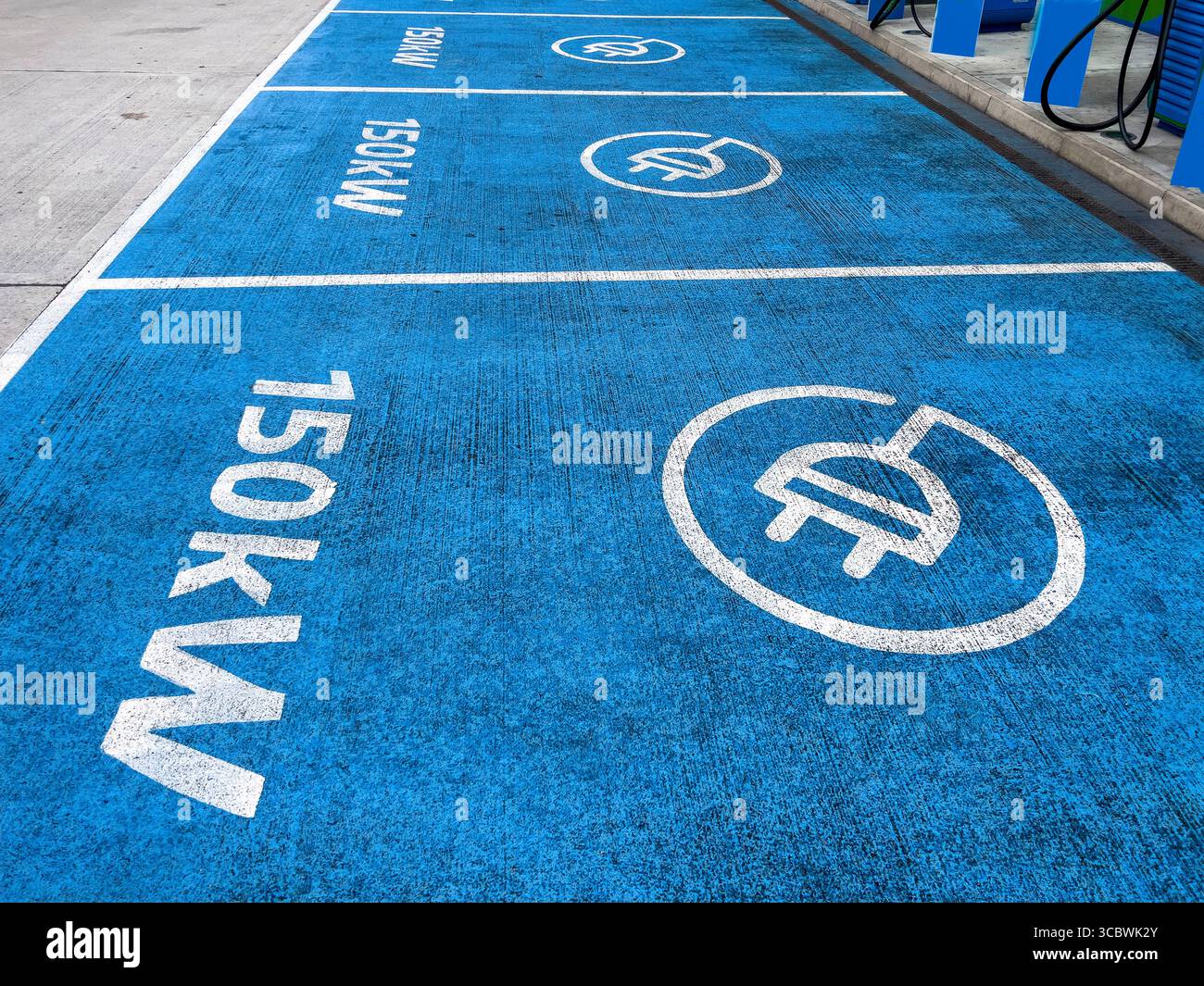 Vista dall'alto del piazzale blu della stazione di ricarica per auto elettriche con grafica a spina e segnaletica da 150 kW sul piazzale del garage Foto Stock