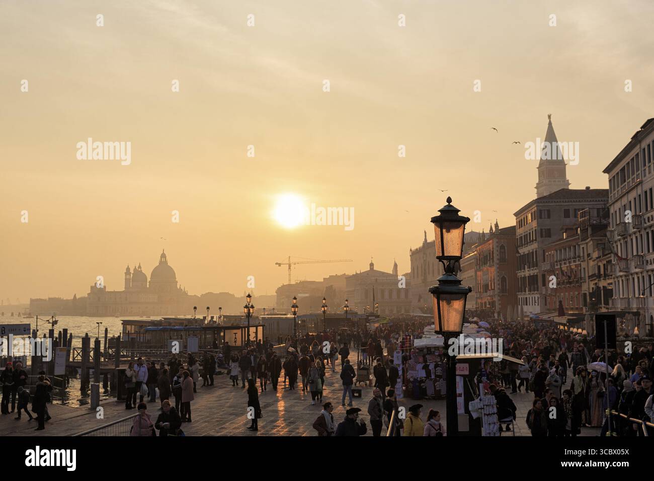 Folla, attracco delle barche a Piazza San Marco, Basilica di San Marco, Chiesa all'orizzonte, tramonto in inverno, retroilluminazione, Venezia, Italia Foto Stock