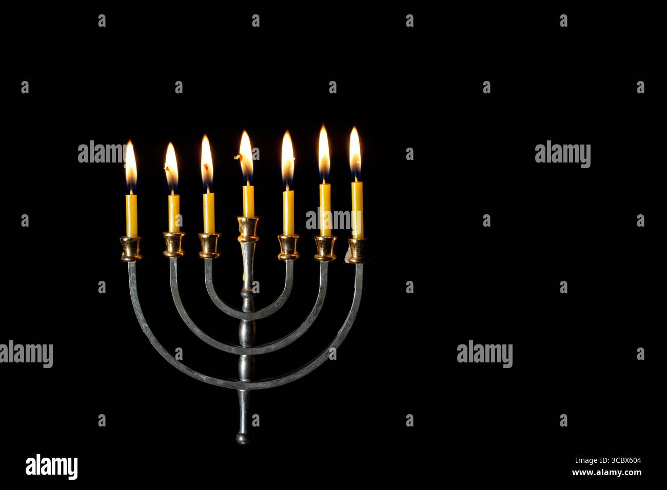 Menorah Hanukkah con candele accese su sfondo nero. Simbolo ebraico. Foto Stock