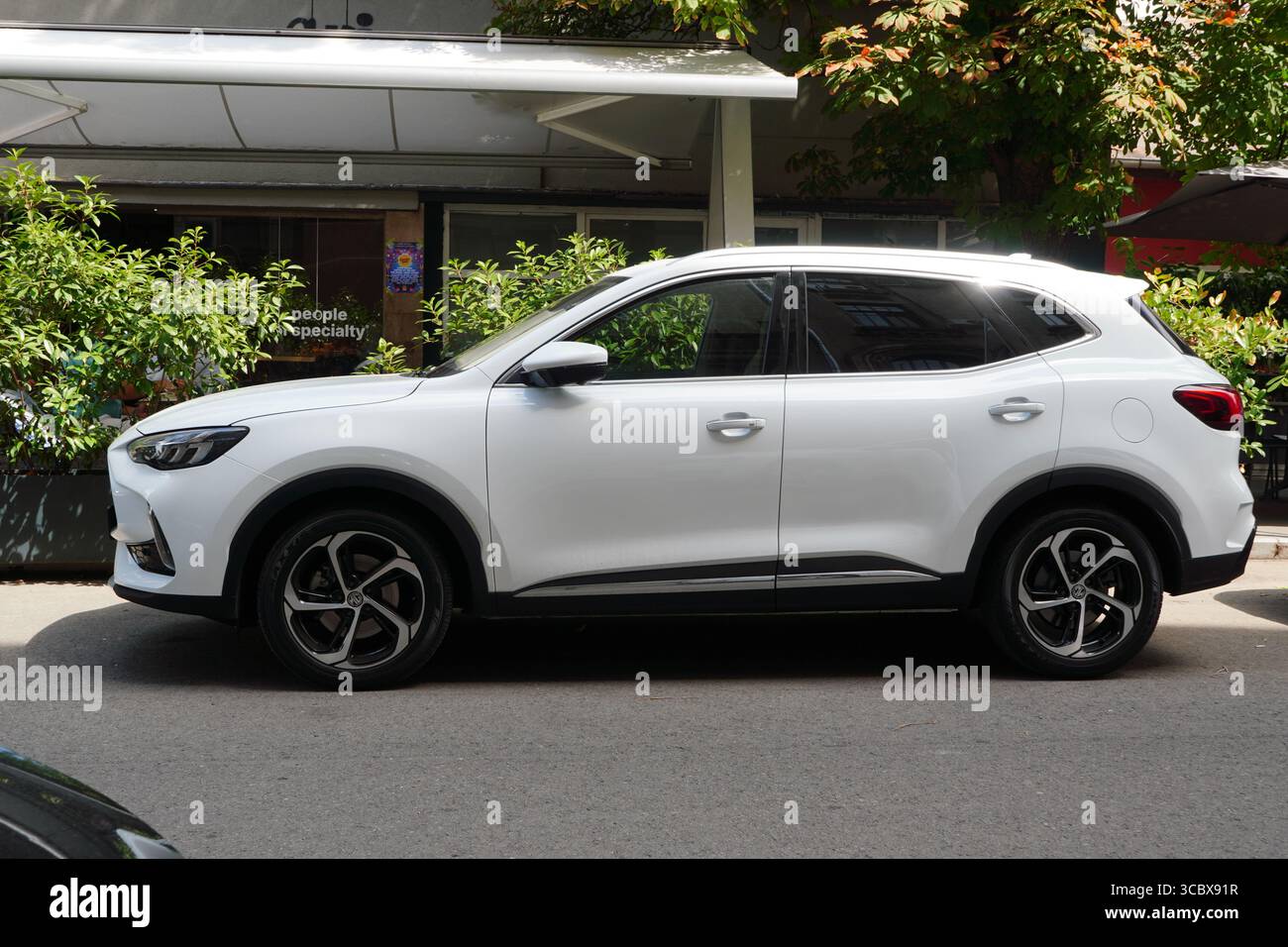 Bucarest, Romania – 6 agosto 2025: Vista ravvicinata della suv bianca MG HS parcheggiata sulla strada di fronte al caffè Foto Stock