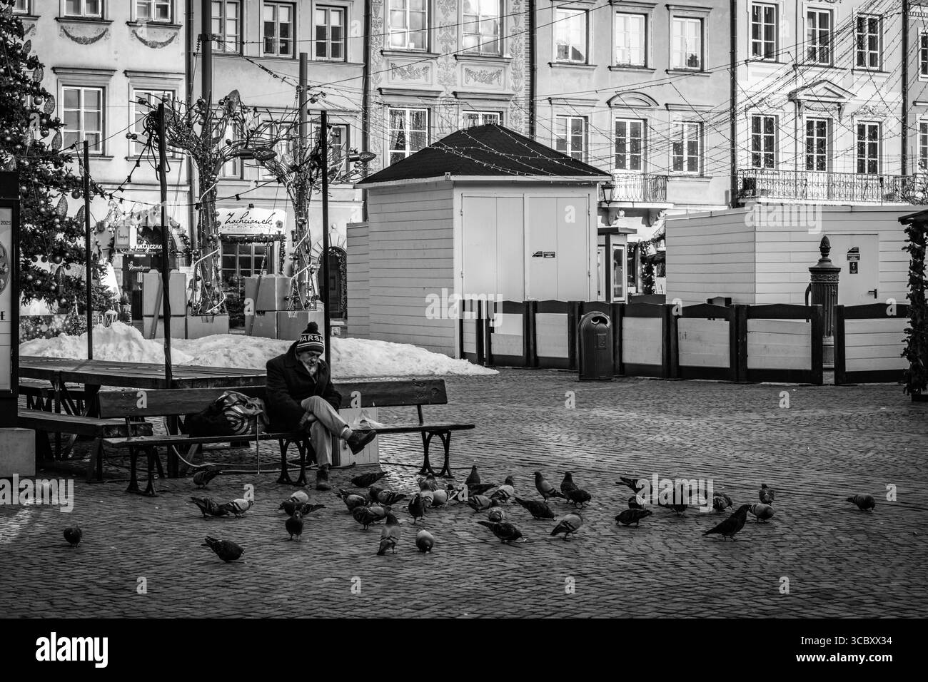 Un vecchio dà da mangiare ai piccioni nella piazza della città vecchia di Varsavia Foto Stock