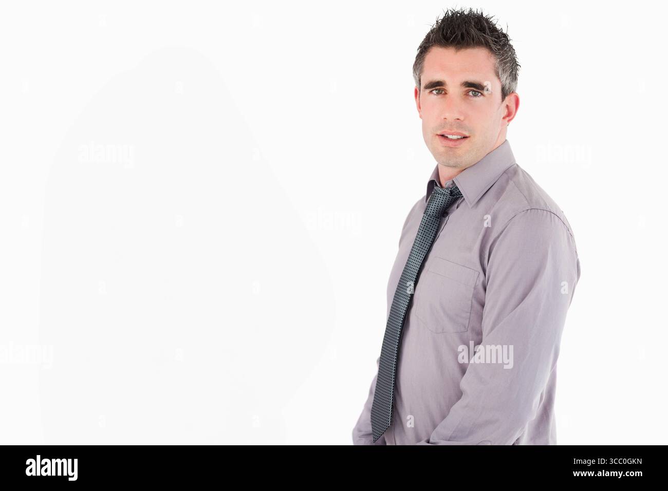 Uomo in piedi su uno sfondo bianco con camicia viola chiaro e cravatta a motivi geometrici, spazio copia Foto Stock Uomo in piedi su uno sfondo bianco con camicia viola chiaro e cravatta a motivi geometrici, spazio copia Foto Stock