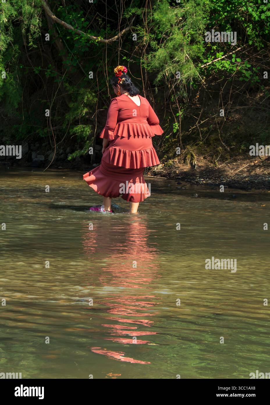 Huelva, Andalusia, Spagna. 4 giugno 2025. Donna anziana in abito flamenco che tenta di attraversare il guado del fiume Quema durante il pellegrinaggio annuale Foto Stock
