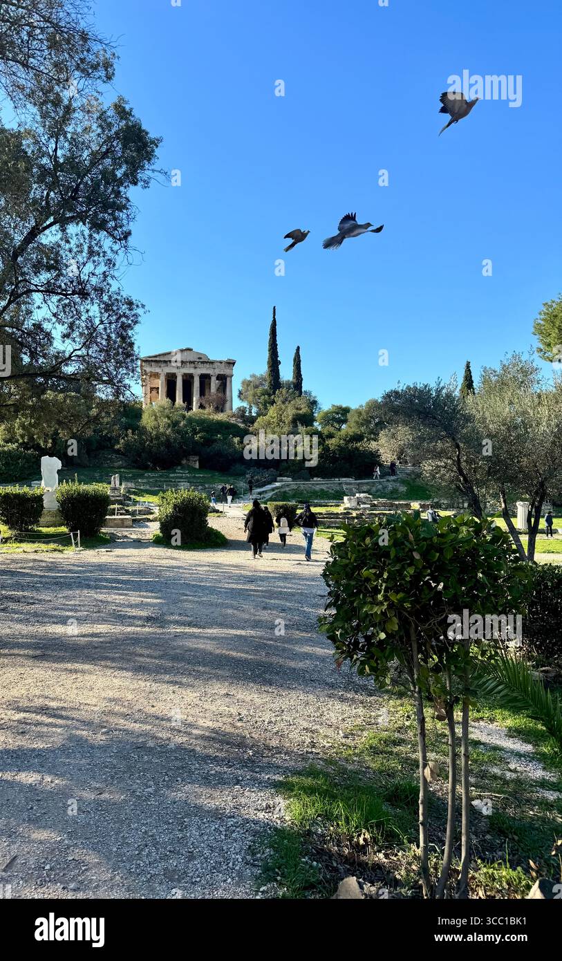 Vedute dell'antica Agorà di Atene, con le sue rovine storiche e il Tempio di Efesto, con i visitatori che esplorano il sito. - Immagine stock catturata con smartphone