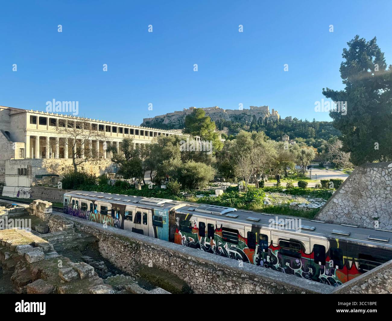 Atene Antica Agorà con passaggio del treno della metropolitana e l'Acropoli sullo sfondo, Grecia. Foto Stock