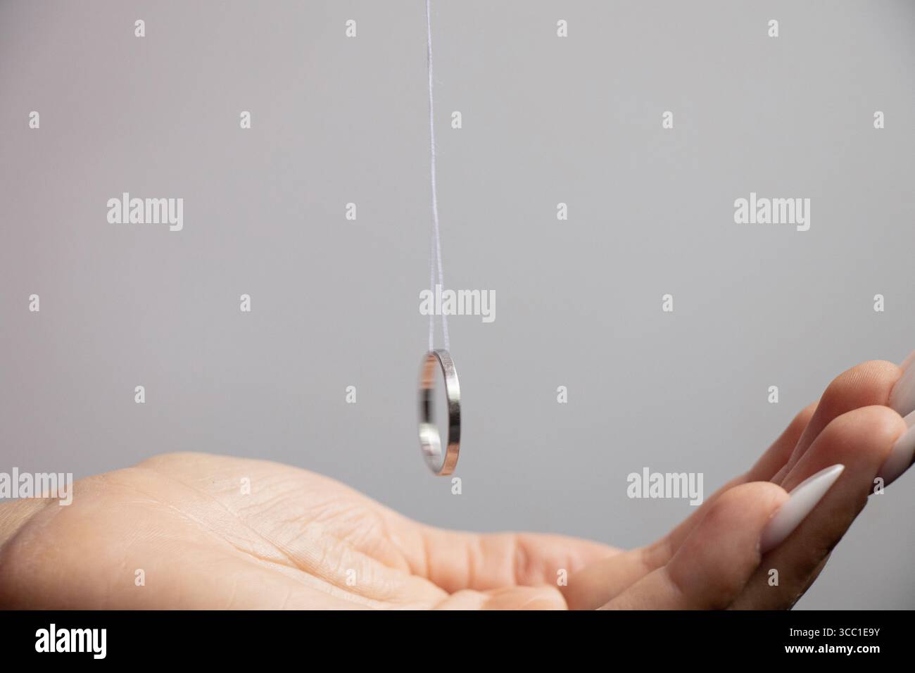Rituale con un anello su una corda tra le mani delle donne, primo piano Foto Stock