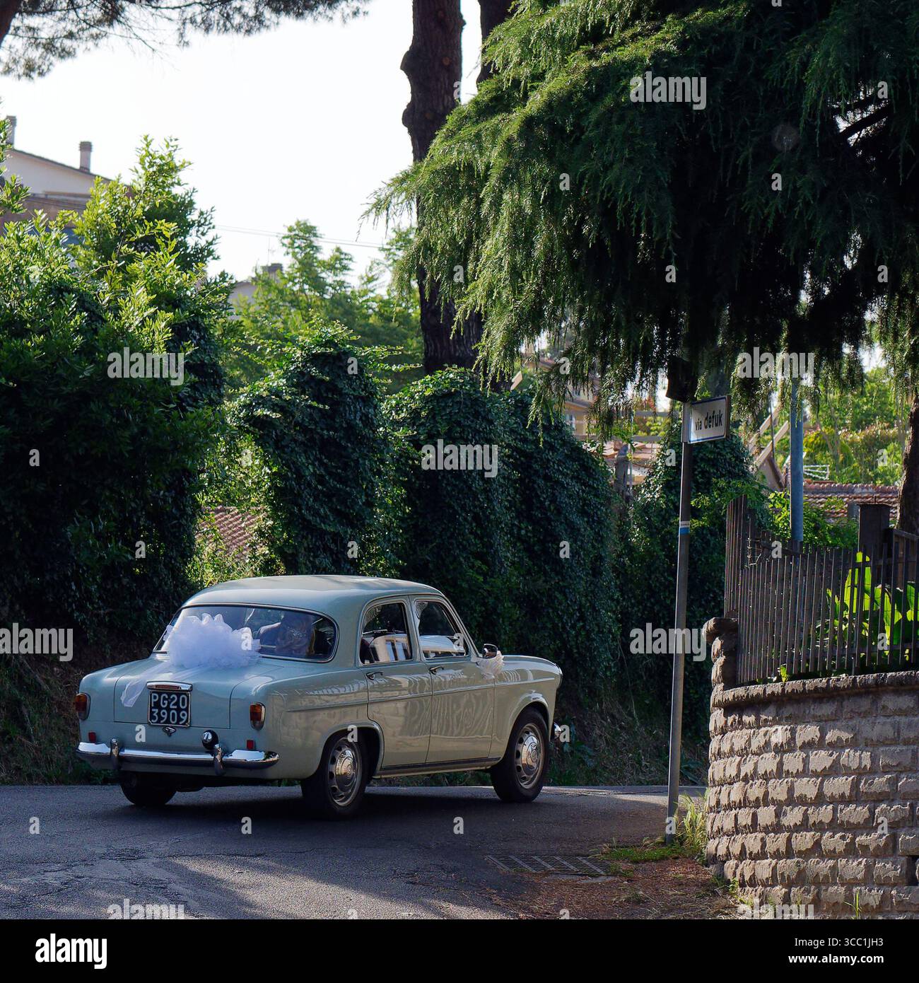 Elegante auto da sposa classica con nastri bianchi lascia la chiesa di Montefascone, regione Lazio, Italia. 7 giugno 2025 Foto Stock