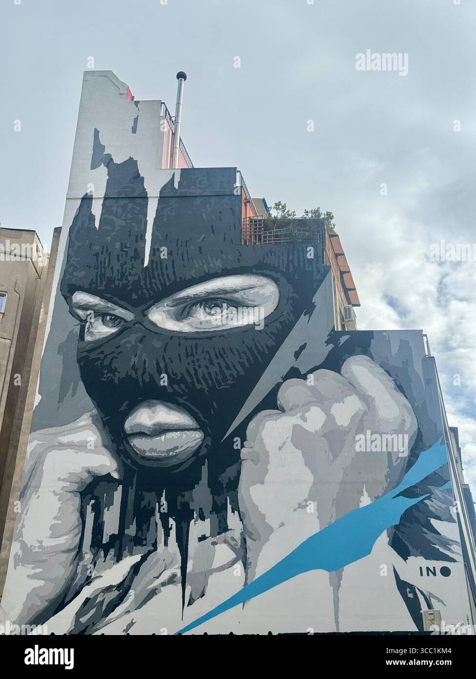 Murale di Street art su un edificio di Atene, con un ritratto suggestivo di una donna in una balaclava. - Immagine stock catturata con smartphone