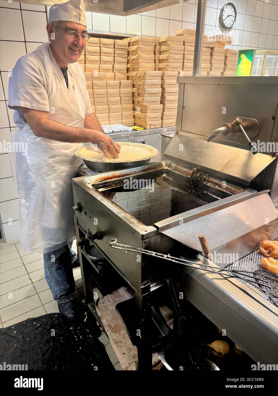Uomo che prepara loukoumades nella cucina di Krinos, una panetteria storica ad Atene, in Grecia. - Immagine stock catturata con smartphone