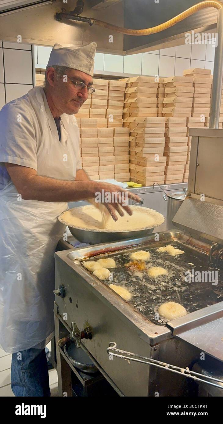 Uomo che prepara loukoumades nella cucina di Krinos, una panetteria storica ad Atene, in Grecia. - Immagine stock catturata con smartphone