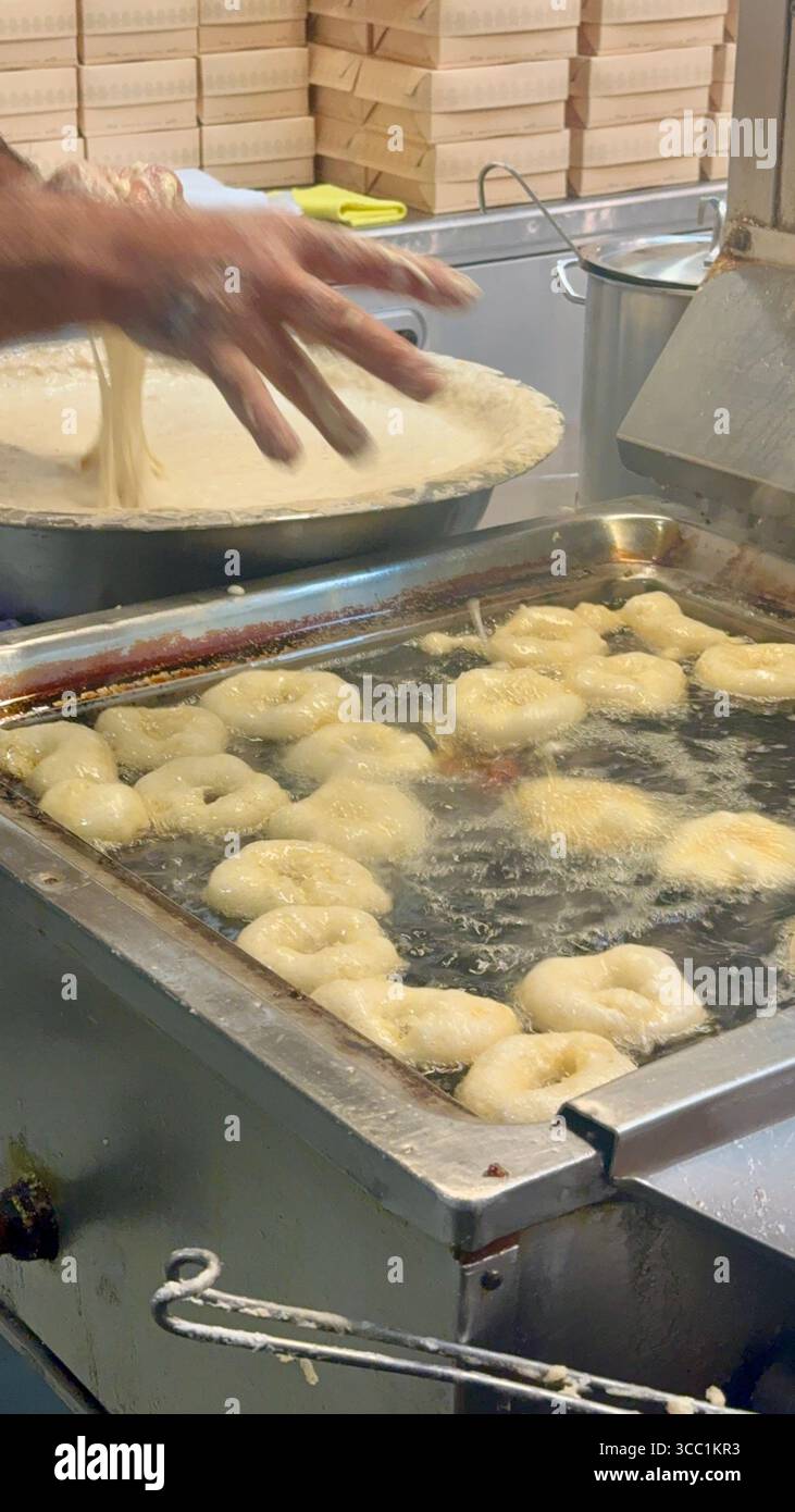 Uomo che prepara loukoumades nella cucina di Krinos, una panetteria storica ad Atene, in Grecia. - Immagine stock catturata con smartphone