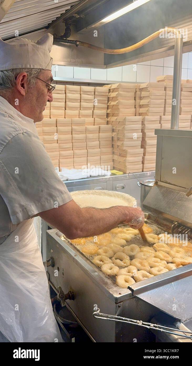 Uomo che prepara loukoumades nella cucina di Krinos, una panetteria storica ad Atene, in Grecia. - Immagine stock catturata con smartphone