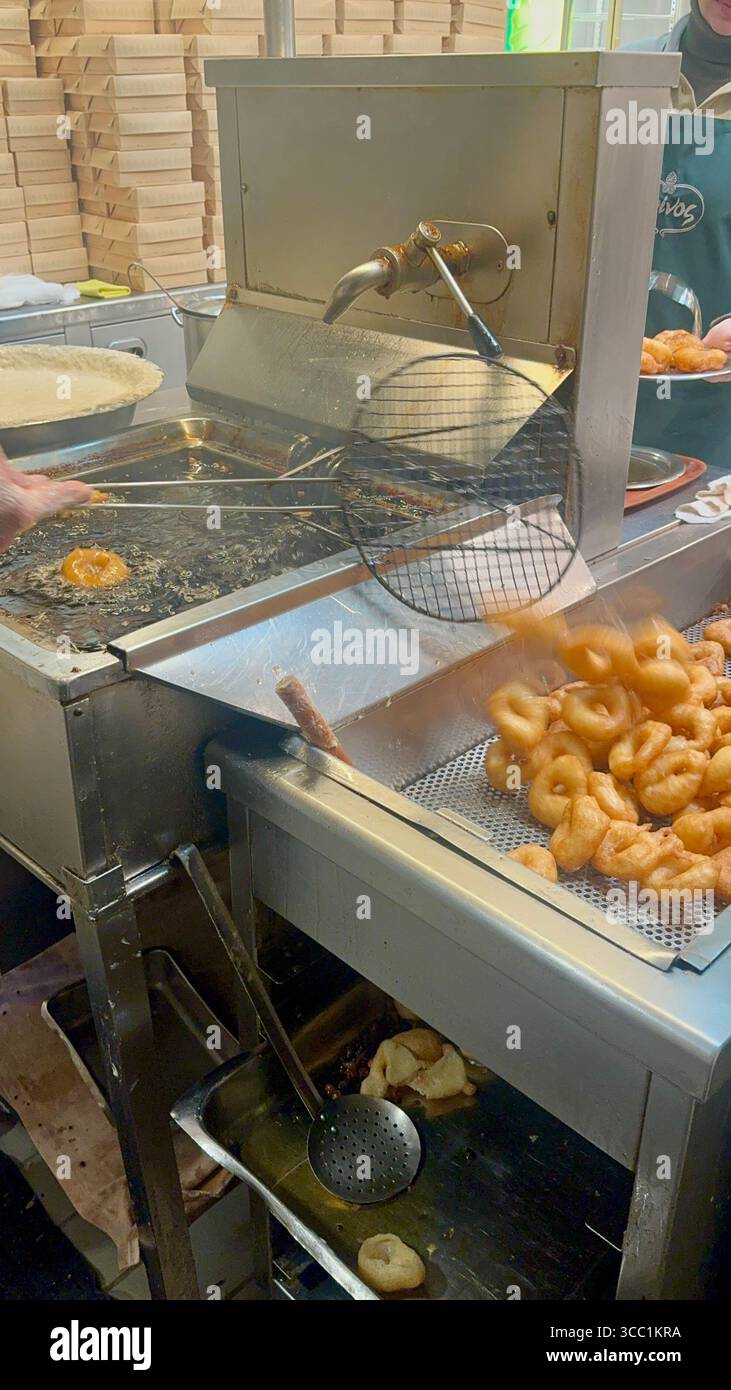 Uomo che prepara loukoumades nella cucina di Krinos, una panetteria storica ad Atene, in Grecia. - Immagine stock catturata con smartphone