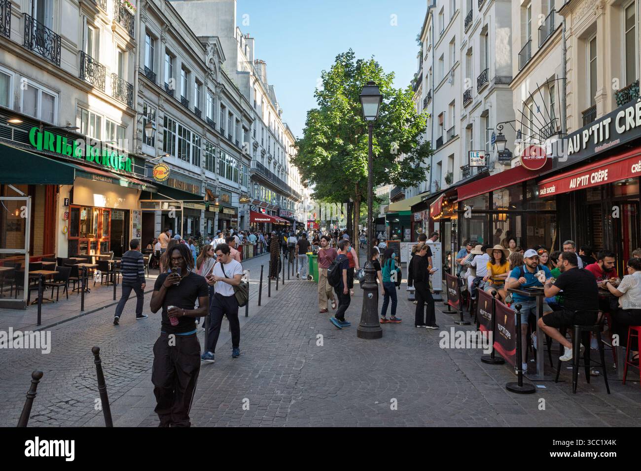 Una vivace strada pedonale a Parigi, in Francia, con gente che fa shopping e cena in ristoranti all'aperto. Foto Stock