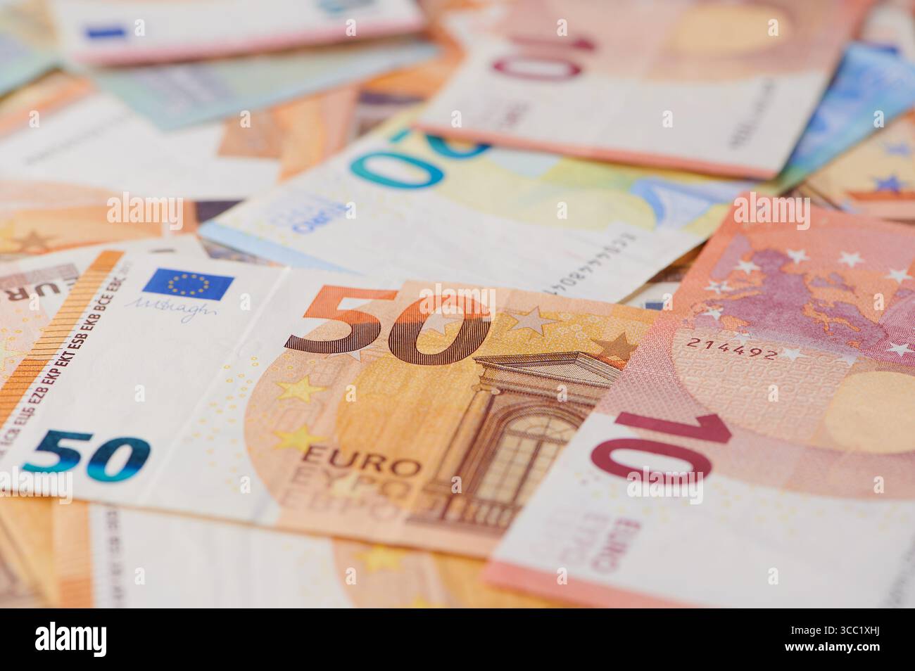 Varie banconote in euro sono sparse su una superficie in piena luce Foto Stock