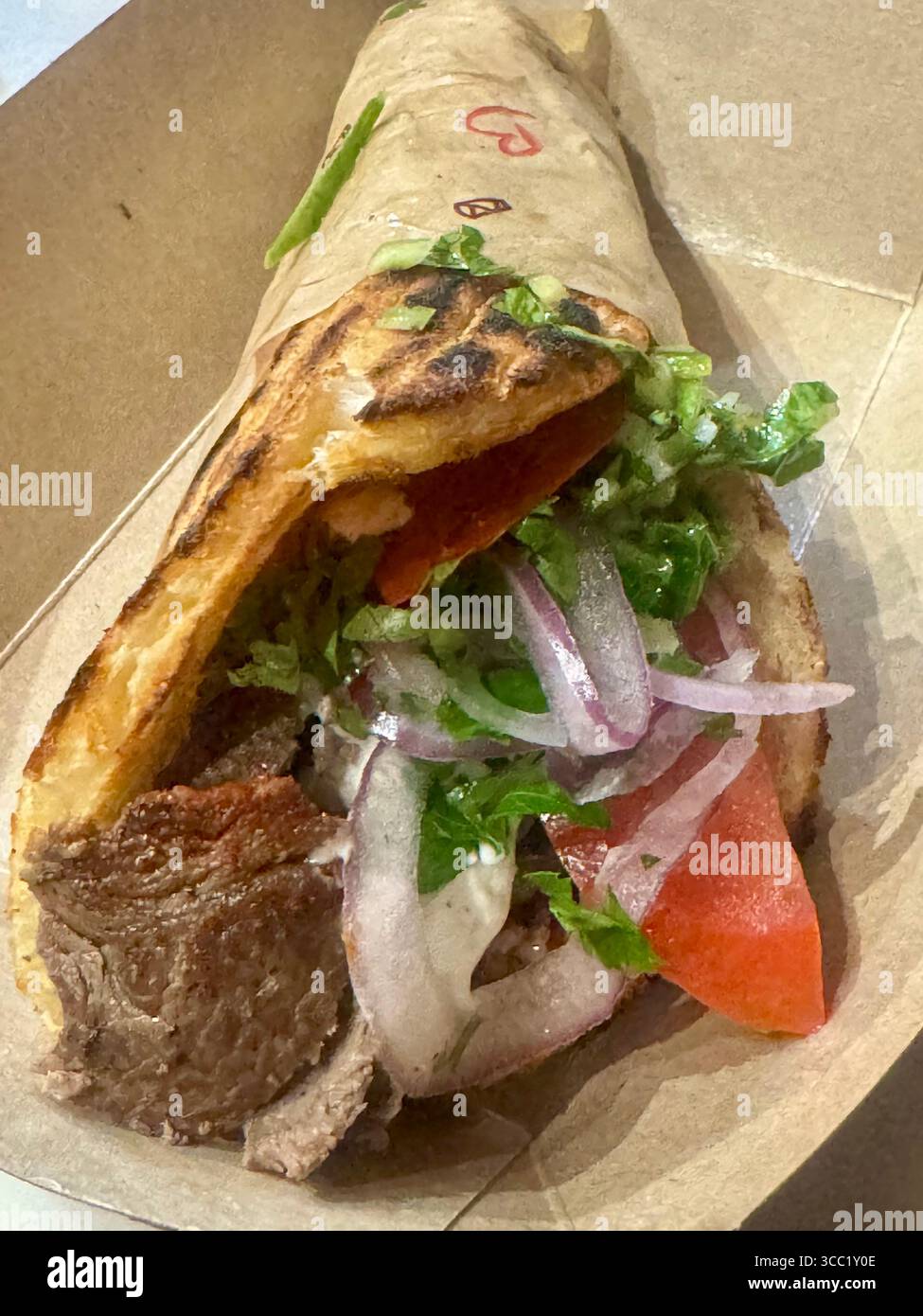 Tradizionale gyro di manzo greco avvolto in pita grigliata con verdure fresche. - Immagine stock catturata con smartphone