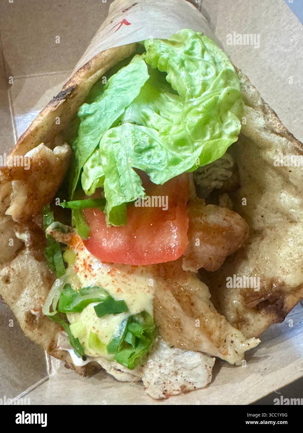 Giroscopio di pollo greco con pita grigliata, lattuga, pomodoro e salsa. - Immagine stock catturata con smartphone