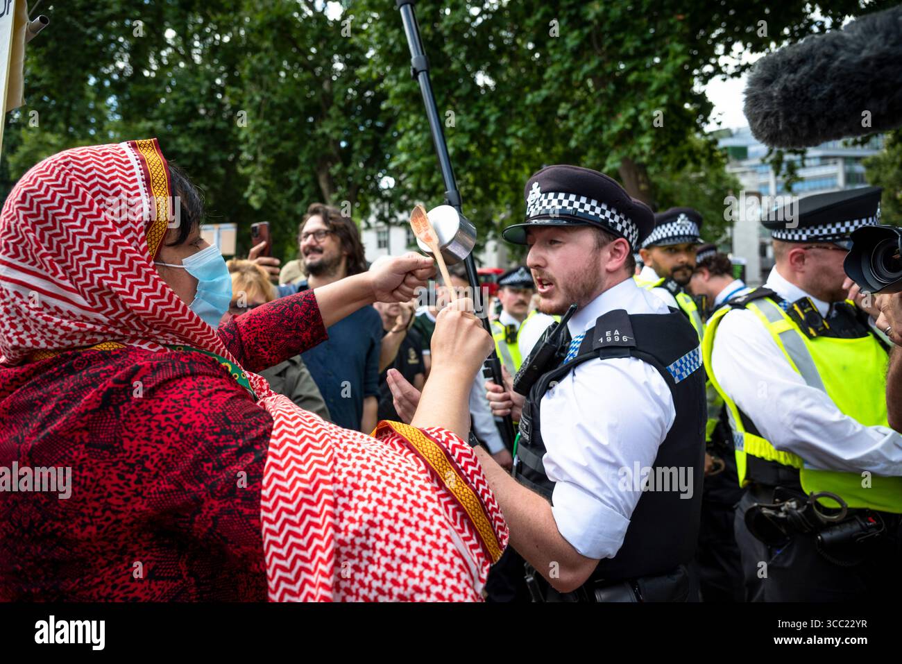 Donna che segue un poliziotto e gli sbatte una minuscola pentola nell'orecchio, Palestine Action Protestation in Parliament Square, Londra, Inghilterra, Regno Unito, 09/08/2025 Foto Stock