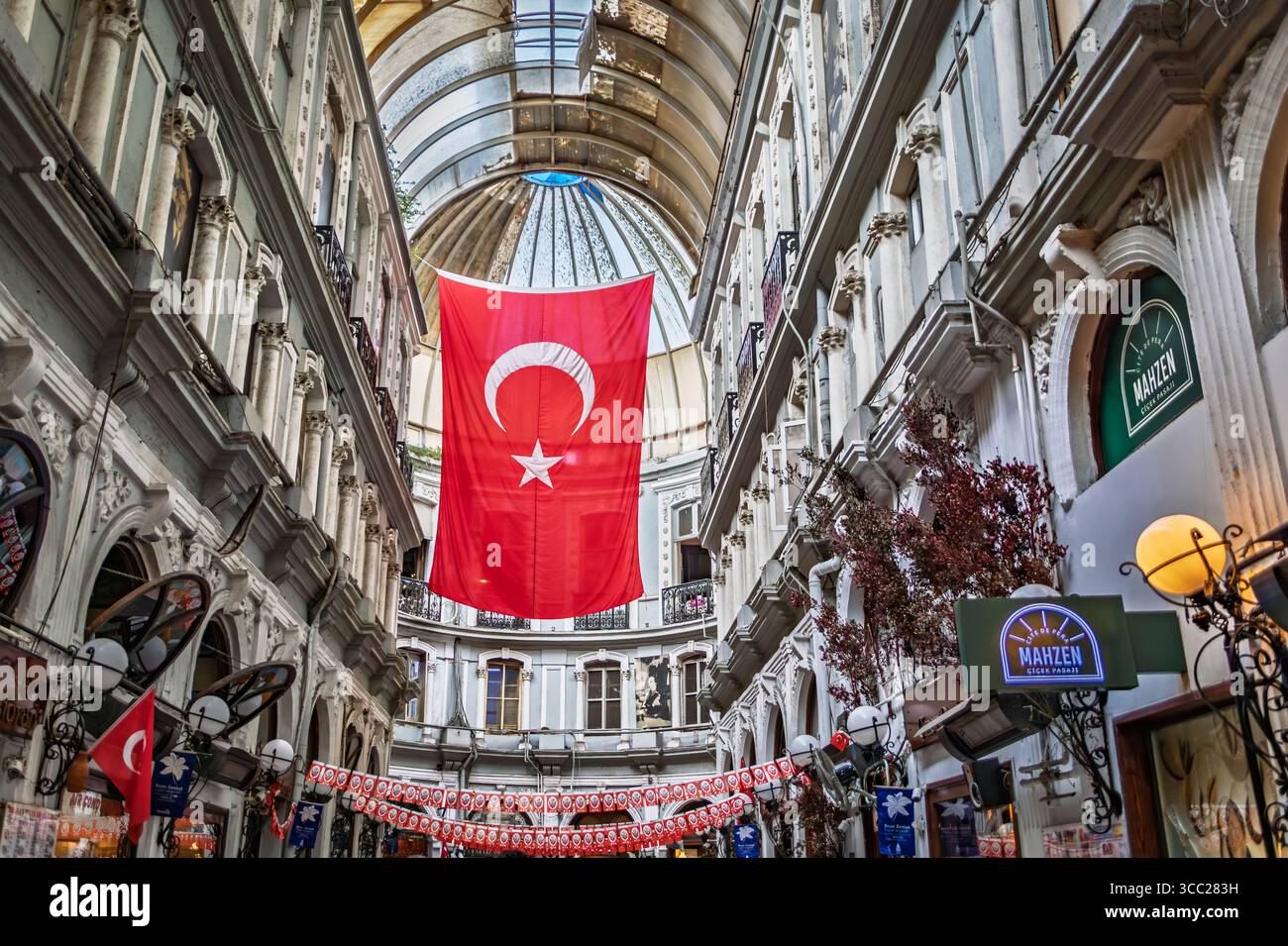 Istanbul, Turchia - 11 novembre 2023: Interni ornati dello storico passaggio coperto Cicek Pasaji, una grande bandiera turca appesa al tetto di vetro Foto Stock