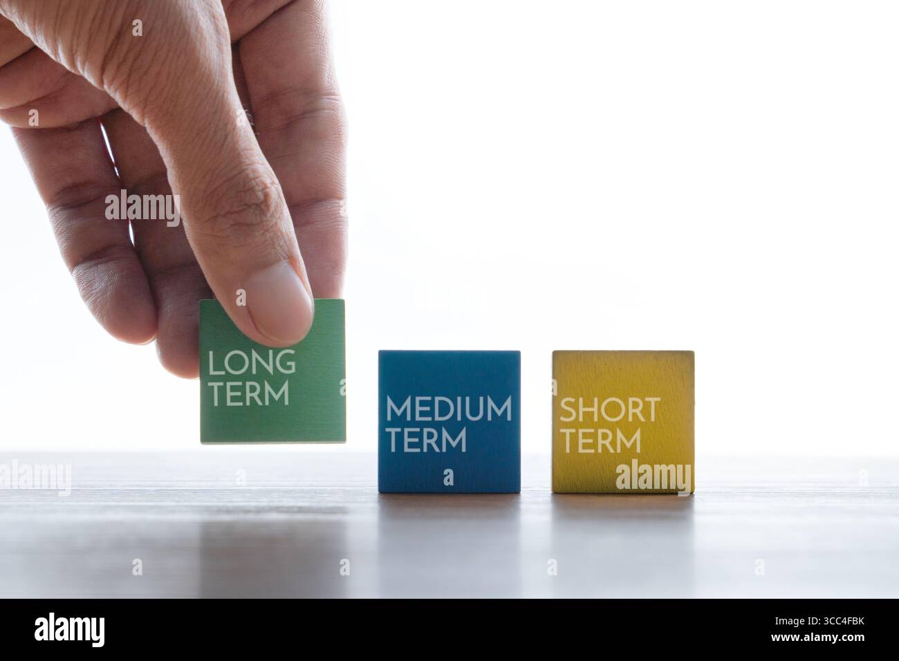 Scegliere a mano un cubo di legno con testo A LUNGO TERMINE. Concetto di investimento. Foto Stock